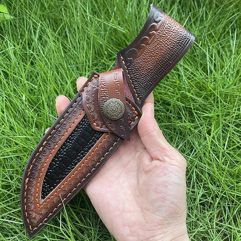 Hand holding Rugged Leather Knife Sheath For Fixed Blade Knives With Secure Buckle Scabbard Pouch on grass background