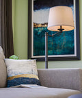 Riverside Copper Bronze Swing Arm Floor Lamp With Cozy Warm Glow Oatmeal Drum Shade beside a sofa in a living room corner.