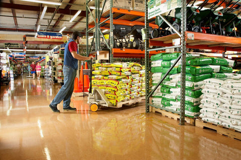 Person using a Hand Pallet Jack 5000 Lb Capacity With Roller Entry And Exit Ramp Tapered Fork Tips No Maintenance Sealed Bearings in warehouse.