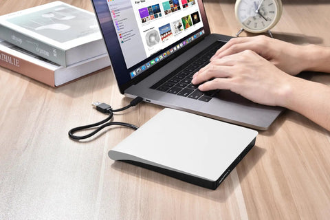 Plug And Play External CD DVD Drive For Mac And Laptop With USB Three Point Zero And USB C No Driver Required Slim White Optical Drive For PC And MacBook Ready Out Of The Box., slim white external CD/DVD drive connected to a MacBook
