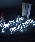 "Youre Like Really Pretty White LED Neon Sign For Wall Decor With Adjustable Brightness Levels Dope Vibe For Bachelorette Party Engagement Wedding Bar Birthday Party Home Cave Pub Restaurant" glowing in dark with books