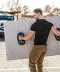 Man using Portable Electric Vacuum Suction Cup Lifter For Wood Tile Marble Drywall Heavy Duty Hand Tool to carry large drywall sheet.