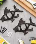 Dead Reliable Cast Iron Fish Wall Hooks 2 Pack, matte brown fish coat hangers on table with tools.