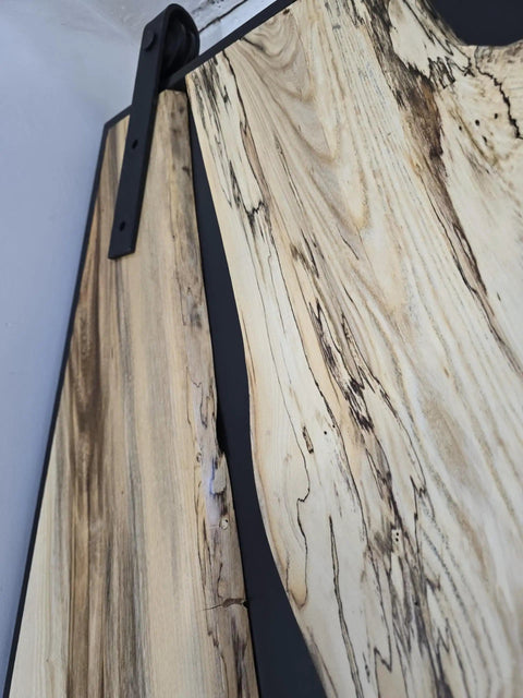 Close-up of Handcrafted Live Edge Spalted Hackberry Barn Door With Custom Sizing Made To Order In Minnesota Totally One Of A Kind Rustic Modern Wood Door For Hallway Or Entryway showing wood grain and metal hardware.