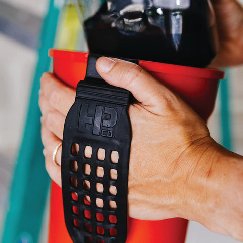 Grab And Go 32 Ounce Paint Pail With Magnetic Brush Holder And Built In Scraper, hands holding the red pail and black strap