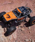 Capra UTB18 One Eighteenth Scale RC Crawler 4WD RTR on rocky terrain, featuring tube chassis and multicolor gray design.