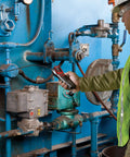 Technician using Combustible Gas Handheld Detector with 16 inch flexible probe on industrial pipes for gas leak detection.