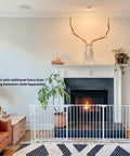 Extra Wide Walk Through Baby Gate, Customizable Safety Barrier fits from 35.4 to 82.7 inches, shown in front of fireplace, white.