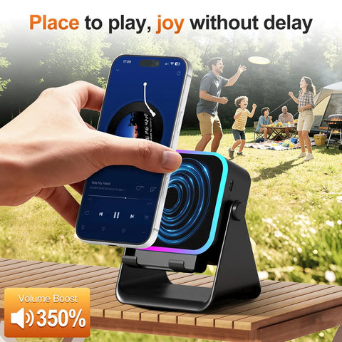 Induction Phone Stand Speaker With Colorful Lights And 3500mAh Battery Portable Hands Free Amplifier For iPhone iPad Android Samsung No Bluetooth Hassle Required on an outdoor table with a phone playing music, family in background.