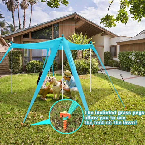 Beach Canopy Tent 11 By 11 Ft With 6 Sandbags, set up on a lawn with stability poles, orange pegs visible, two people and a dog underneath.
