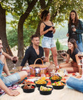 Group enjoying outdoor picnic with Meal Prep Containers With Lids 50 Pack 32 Ounce Round To Go Food Storage Bowls on blanket.
