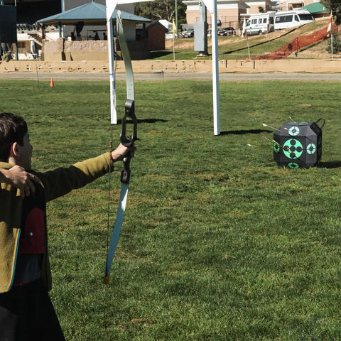 Child aiming at 15x15 All-Side Archery Target Block Portable Crossbow Practice Target With Carry Handle, on outdoor field