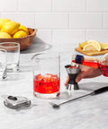 Using Stainless Steel Two Sided Jigger With Flip Measurements, Soft Non Slip Grip to pour drink into mixing glass on counter.