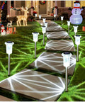 Solar LED Outdoor Stake Lights Pack Of 10 Waterproof Stainless Steel illuminating a garden path at night, holiday decorations visible.