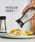 Go-To Salt And Pepper Shaker Set With Stainless Steel Caps And Glass Bottles, hand using salt shaker over pasta