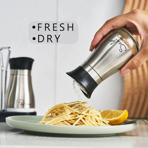 Go-To Salt And Pepper Shaker Set With Stainless Steel Caps And Glass Bottles, hand using salt shaker over pasta