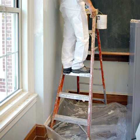 Painter on ladder with SuperTuff Plastic Drop Cloth For Big Paint Jobs 9 By 12 Feet covering floor to protect from paint spills.