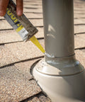 Applying All Weather Clear Roof Sealant 10.5 Oz Cartridge Pack Of Twelve to a pipe on shingles for waterproof sealing.