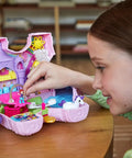 Child playing with Unicorn Party Playset With 25 Surprises, pink unicorn toy with purple hair, open to reveal castle adventure scene