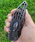 Pocket Folding Knife With 3D Embossed Skull Pattern, intricate handle detail, outdoor background, 3.6 Inch Razor Sharp 440 Blade