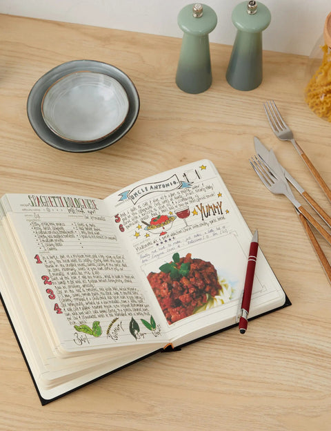 Premium Hardcover Blank Recipe Book For Your Own Creations A DIY Family Cookbook open on a kitchen table with utensils.