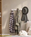 Heavy Duty Wall Mount Coat Rack Featuring Five Lock Down Hooks For All Your Everyday Essentials Like Hats Keys Wallets And Bath Towels Crafted From Corrosion Proof Aluminum In Crisp White Two Pack Bundle with jackets and a hat in a bedroom setting.