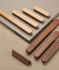 Various wooden drawer knobs and handles on display, showcasing different wood tones and styles on a neutral background.