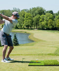 Golfer using Big 23 By 16 Inch Foldable Golf Hitting Mat With 2 In 1 Turf For Rough And Fairway Practice on outdoor course
