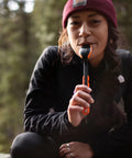 Person outdoors holding TrailSpoon Extendable Backpacking Spoon With Silicone Edge For Pots Reach Inside Cookware during camping trip.