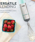 5 Speed 330 Watt Immersion Hand Blender With Stainless Steel Blades And Whisk Attachment For Soups Smoothies And Purees in aqua next to strawberries.