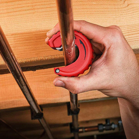 Close-up of red copper tubing cutter on a copper pipe during cutting.
