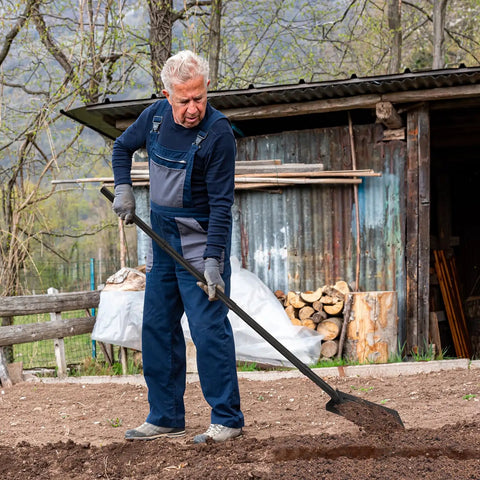 Man using narrow trenching spade with 56 inch long handle and 4 inch wide V shaped blade for digging in his yard