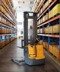 Full Electric Pallet Stacker And Straddle Forklift With 3300 LB Capacity And 220 Inch Lift inside a warehouse aisle.