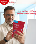 Man holding Max Fresh Wisp Disposable Mini Travel Toothbrushes Peppermint Pack Of 24 No Water Needed in office setting.
