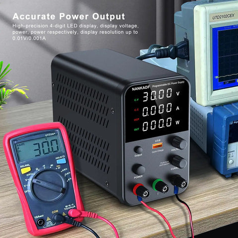 Variable Bench Power Supply With Precision Encoder Knob And Output Enable Disable Button USB Quick Charge Adjustable Voltage And Current Short Circuit Protection Compact Black Boss Grade Unit For Lab And DIY Projects on a wooden desk next to a multimeter.