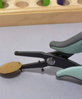 Metal Hole Punch Pliers With Gauge Guard for soft metals, showing 1.25mm hole punch on a brass sheet for jewelry making.