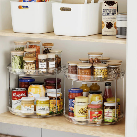 Front view of two-tier clear acrylic Lazy Susan turntables with chrome frame on pantry shelf, holding jars.