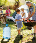 Family barbecuing at campsite with large water jug, using 5 Pack Silicone Water Jug Caps for 3 and 5 Gallon Bottles nearby.