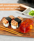 Two Pack Red Musubi Maker Kit Nonstick BPA Free Sushi Mold with completed musubi on wooden board