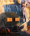 Dual Chamber 43 Gallon Compost Tumbler With Sliding Doors, BPA Free Rotating Batch System For All Season Outdoor Use In Orange, Garden Yard Bin, Easy Turn Design For Faster Rich Soil next to a person working in a garden.