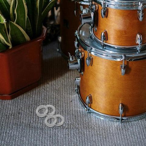 Heavy Duty Metal Wedge Locking Washers For Drum Rack Mounting Hardware and Cymbal Stand secure fasteners next to a wooden drum set.
