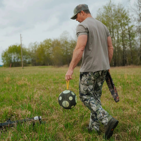 Man carrying Ultra Portable 9 Inch Sand Filled Archery Target With Carry Handle For On The Go Practice Self Balancing Core