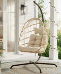 Outdoor Egg Chair With Stand For Patio Backyard Hanging Swing Chair With Foldable Rattan UV Resistant Padded Cushion 350 Lb Capacity Beige Cozy And Chill on a porch