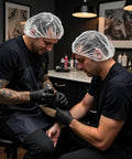Tattoo artists wearing breathable disposable bouffant caps with elastic edge for a secure fit, latex free, in a tattoo shop