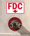 Rugged 12X18 Inch Fdc Fire Department Connection Metal Sign With Down Arrow In Red And White above fire hydrant on wall.