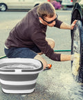 Person washing car with Collapsible 16L Mop Bucket, BPA Free Silicone And PP, heavy duty for portable cleaning