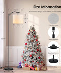 Arched LED Floor Lamp With Beige Linen Shade Slick Modern Mid Century Standing Lamp Black Finish Built In Footswitch Ideal For Living Room Bedroom Study Or Office E26 Base Socket Bulb Not Included Durable Steel Construction next to a decorated Christmas tree