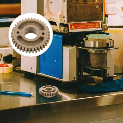 Beefed Up Replacement Gear For Electric Cup Sealing Machines Made From Durable Plastic, Helps Prevent Leaks And Spills, Stable Performance For Beverage Service, Easy Install And Long Lasting Wear, grey gear shown with sealing machine