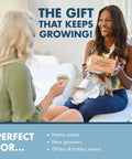 Two women sitting with DIY Indoor Herb Garden Starter Kit, one holding box labeled 'Plant Dreams' and smiling.