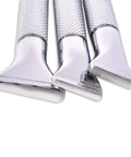 Close-up of three stainless steel razor heads with textured handles in a row